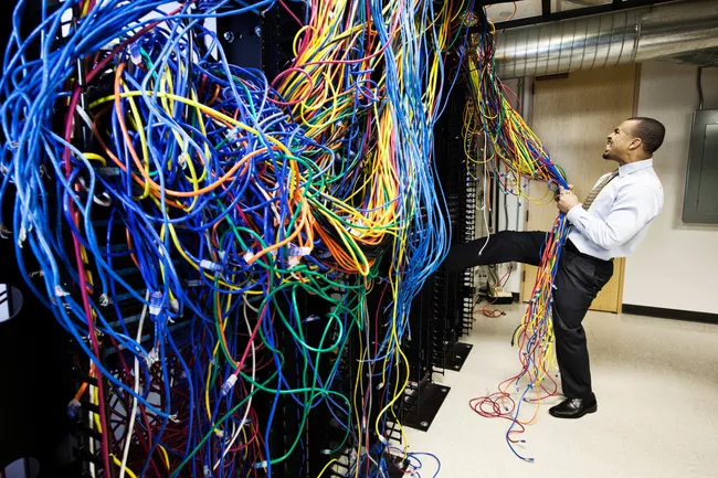 Un técnico atraviesa una maraña de cables CAT-5 en una sala de servidores informáticos